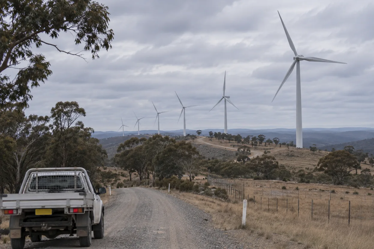 Rows of wind turbines on a ridgeline seen from the site access road, the kind of project this sector runs